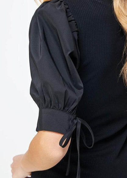Black poplin sleeve knit top. This style features bodice in ribbed knit, a classic V neckline, and & poplin short sleeves with cuff and tie detail.