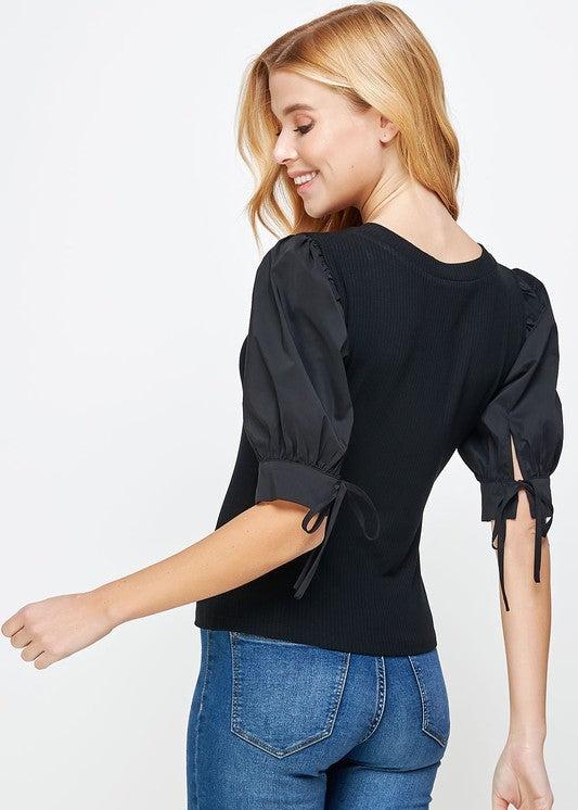 Black poplin sleeve knit top. This style features bodice in ribbed knit, a classic V neckline, and & poplin short sleeves with cuff and tie detail.