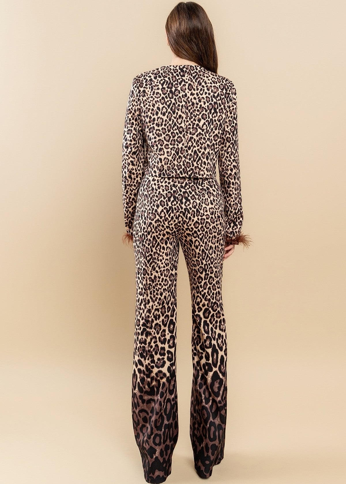 Featuring an all over brown zebra print with ombre design, round neckline, feather trimming as well as a pair of matching pants with a high-rise waist and a wide leg.