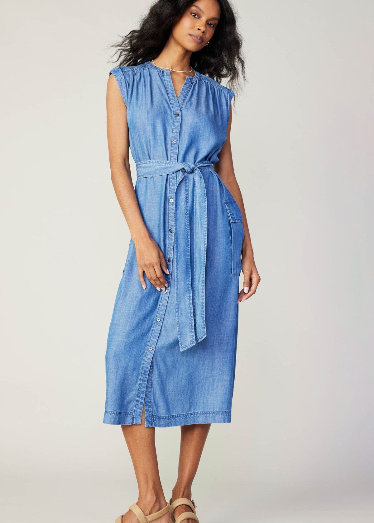 Chambray sleeveless v-neck button down 3/4 length dress with self tie detail on waist and flap pocket on sides.