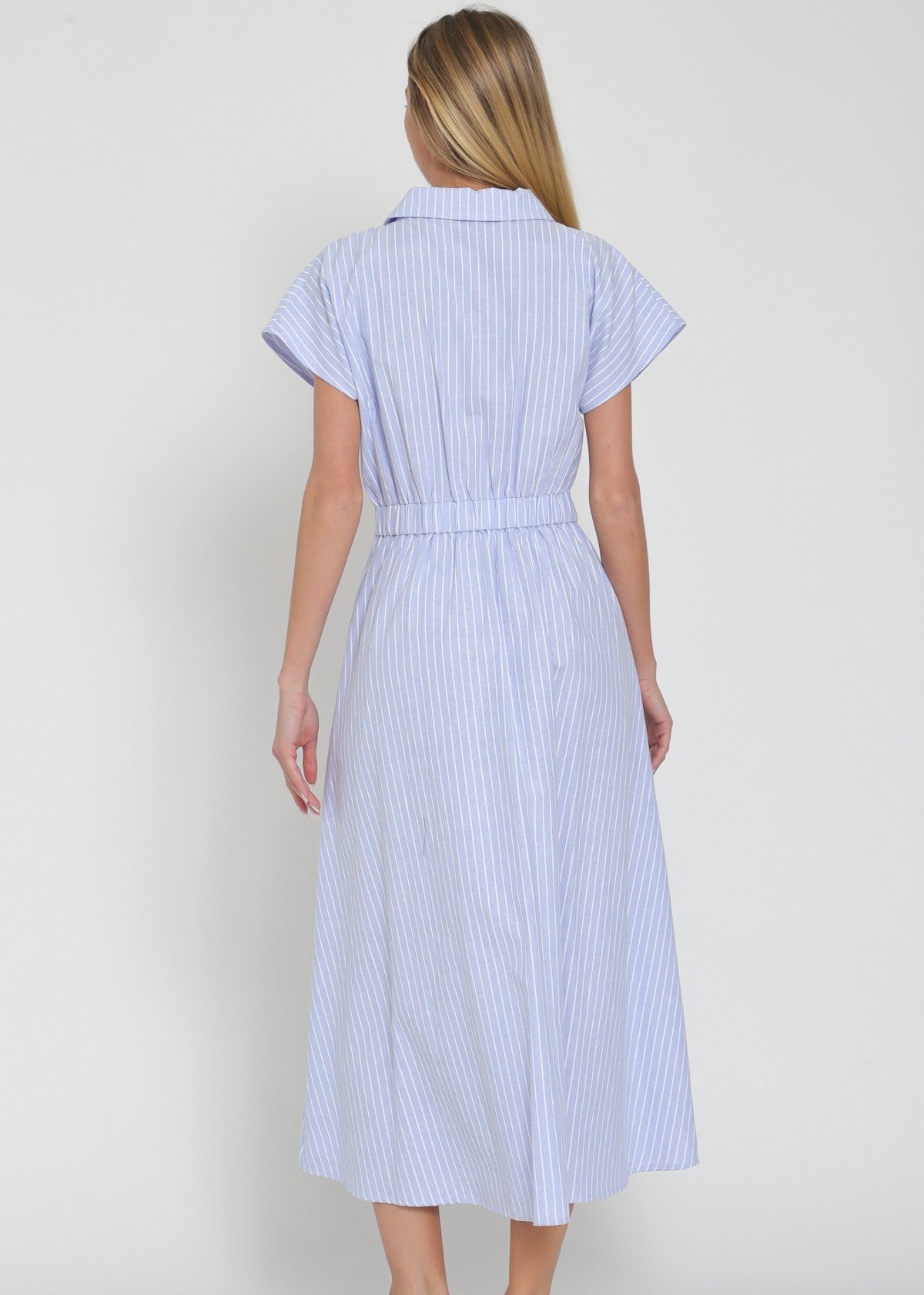 Woman wearing a blue and white striped dress against a plain background