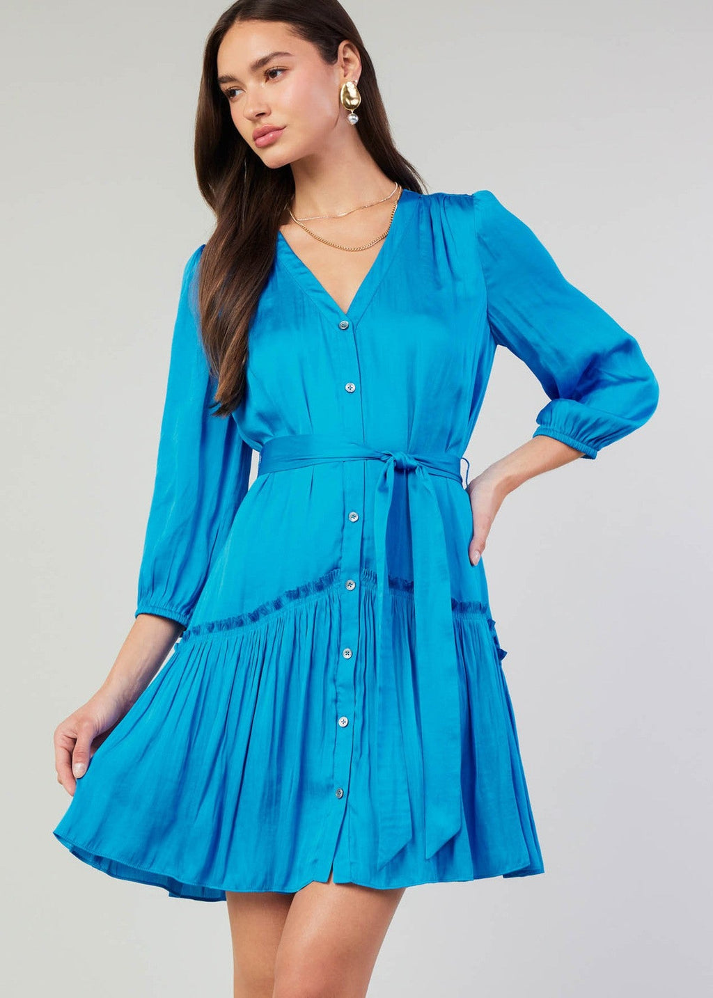 Blue v-neck 3/4 sleeve short button down dress with ruffled detail on skirt.