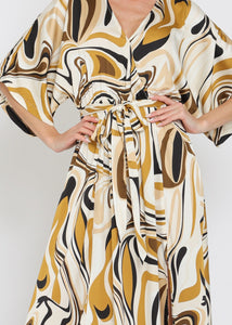 Woman wearing a patterned dress with abstract design on a plain background