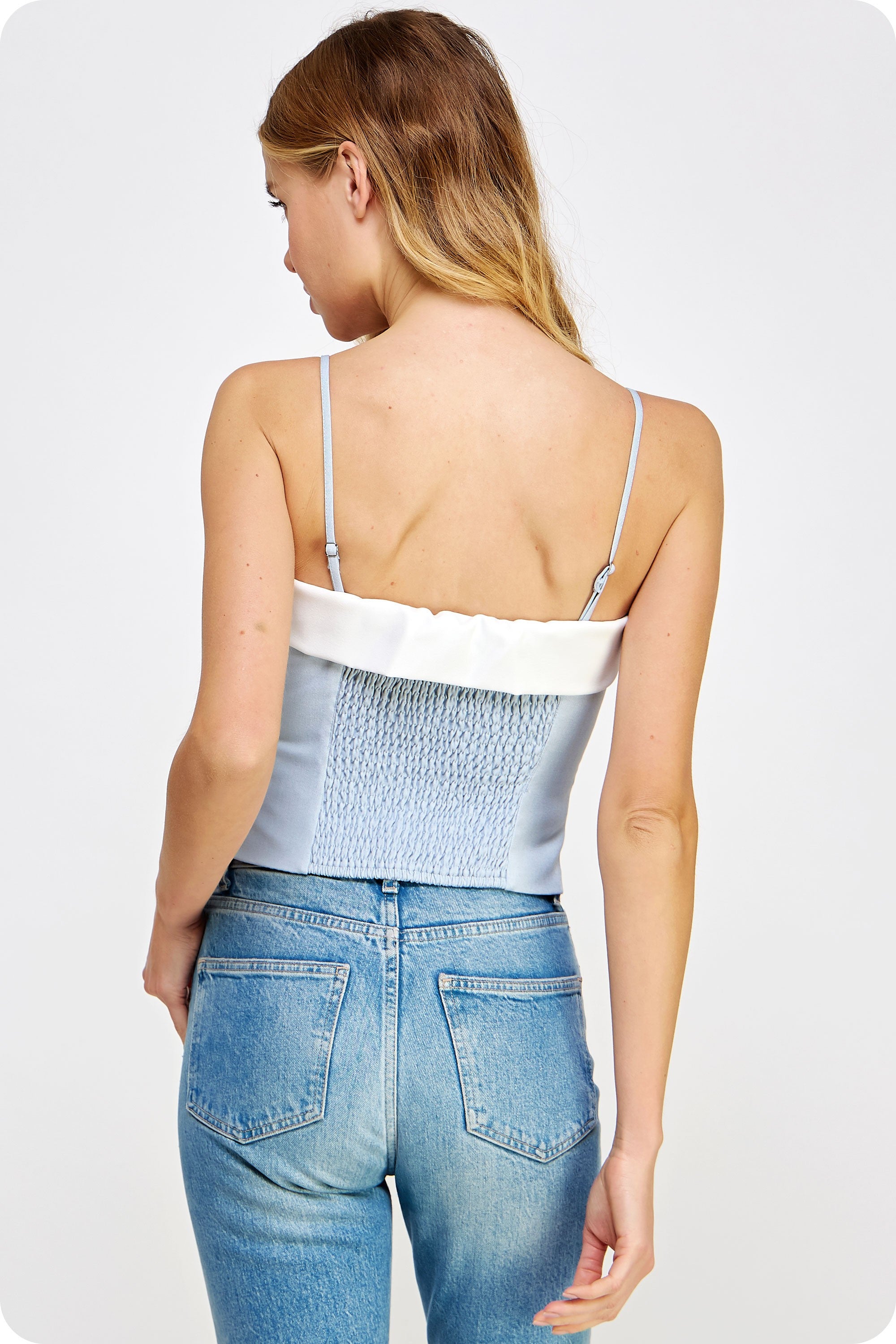 Light chambray contrast color block corset top in suiting twill fabric. This bustier top features contrast fabric detail at bustline, removable adjustable straps, elasticized smocking at back, and button down closure with placket at front. This top can be worn strapless by removing the straps.
