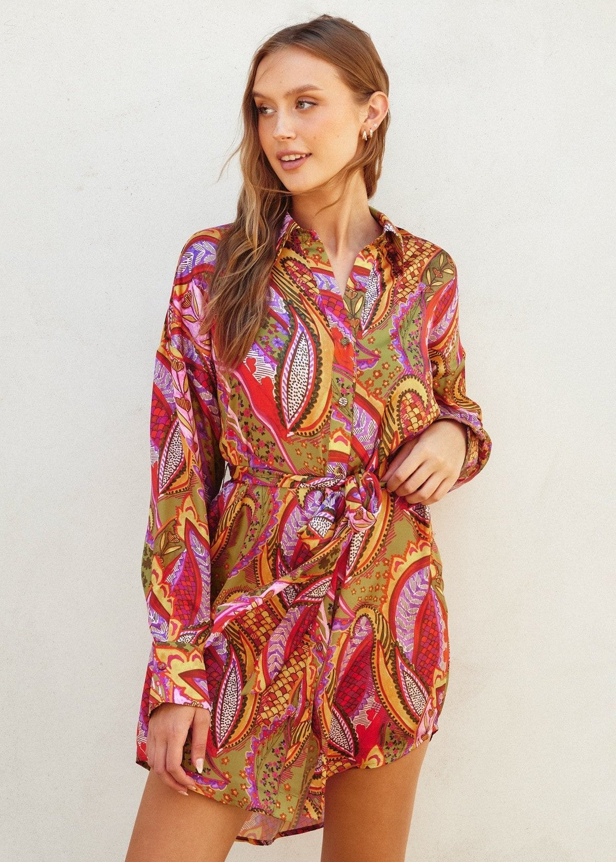 Rio fiesta short shirt dress featuring tropical floral print. Collared. Button down closure. Sash belt.