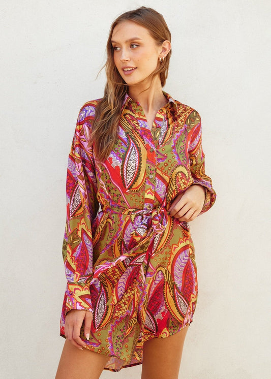 Rio fiesta short shirt dress featuring tropical floral print. Collared. Button down closure. Sash belt.