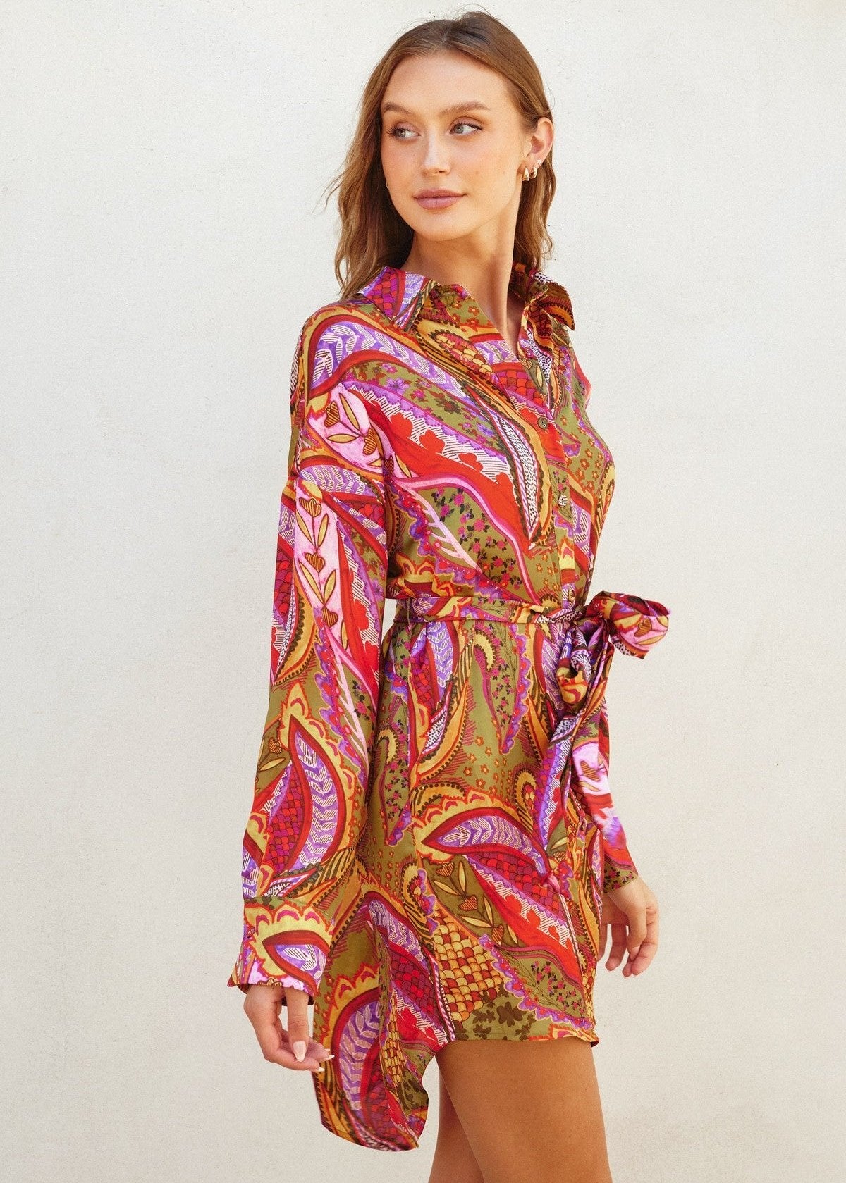 Rio fiesta short shirt dress featuring tropical floral print. Collared. Button down closure. Sash belt.