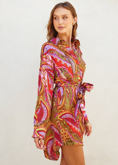 Rio fiesta short shirt dress featuring tropical floral print. Collared. Button down closure. Sash belt.