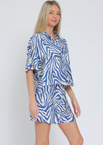 Load image into Gallery viewer, Ivory and blue set featuring short sleeve shirt and elastic waisted shorts.

