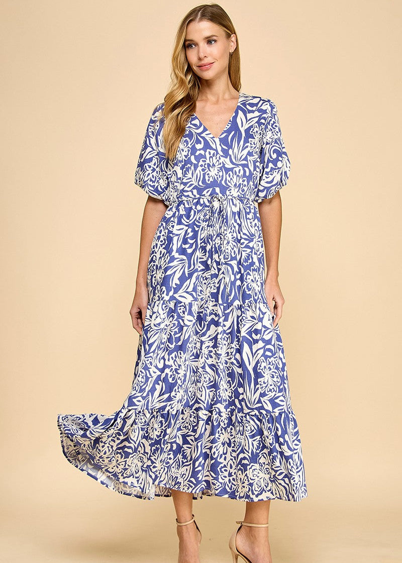 Navy abstract floral print midi dress featuring a V-neck, puffed sleeves, waist tie, and a tiered skirt. Fully lined.