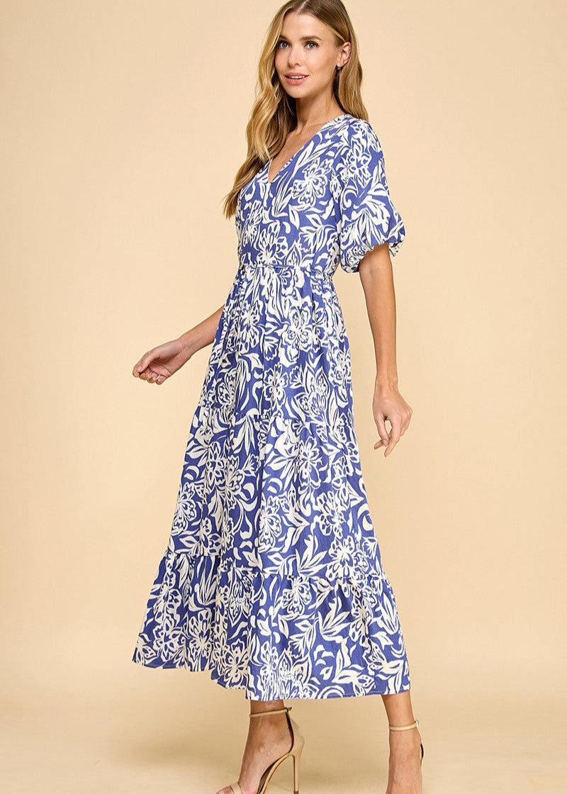 Navy abstract floral print midi dress featuring a V-neck, puffed sleeves, waist tie, and a tiered skirt. Fully lined.