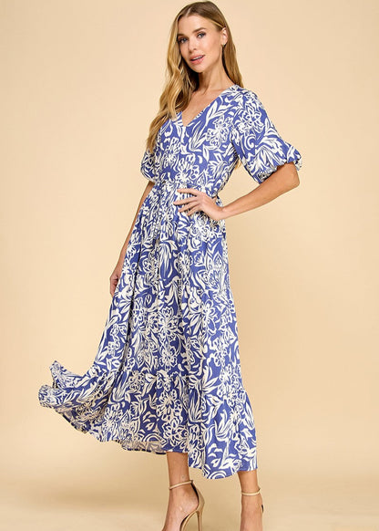 Navy abstract floral print midi dress featuring a V-neck, puffed sleeves, waist tie, and a tiered skirt. Fully lined.