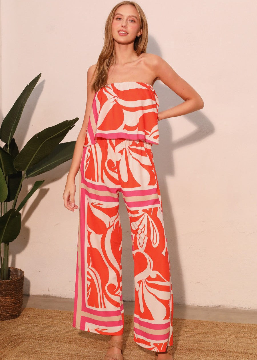 The Sicilia Scarf Cascade Strapless Jumpsuit is a chic and sophisticated one-piece ensemble that combines elegance with modern flair. Featuring a strapless design and a cascading detail, it creates a flattering silhouette while offering effortless movement.