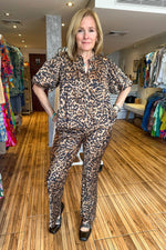 Load image into Gallery viewer, Leopard print two piece set. Leopard pants with matching button up short sleeve top. Everything animal print is super in and this set is no exception.
