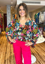 Load image into Gallery viewer, Beautiful and bold, the Lupita Floral print consists of various multicolored flowers against a blackground. The print shapes the evergreen blouse with roomy full sleeves and a shallow V neckline. The bodice maintains a relaxed fit with an elastic waist to create a peplum silhouette. Wear it to work or out to brunch along with black trousers and cute strappy heels.
