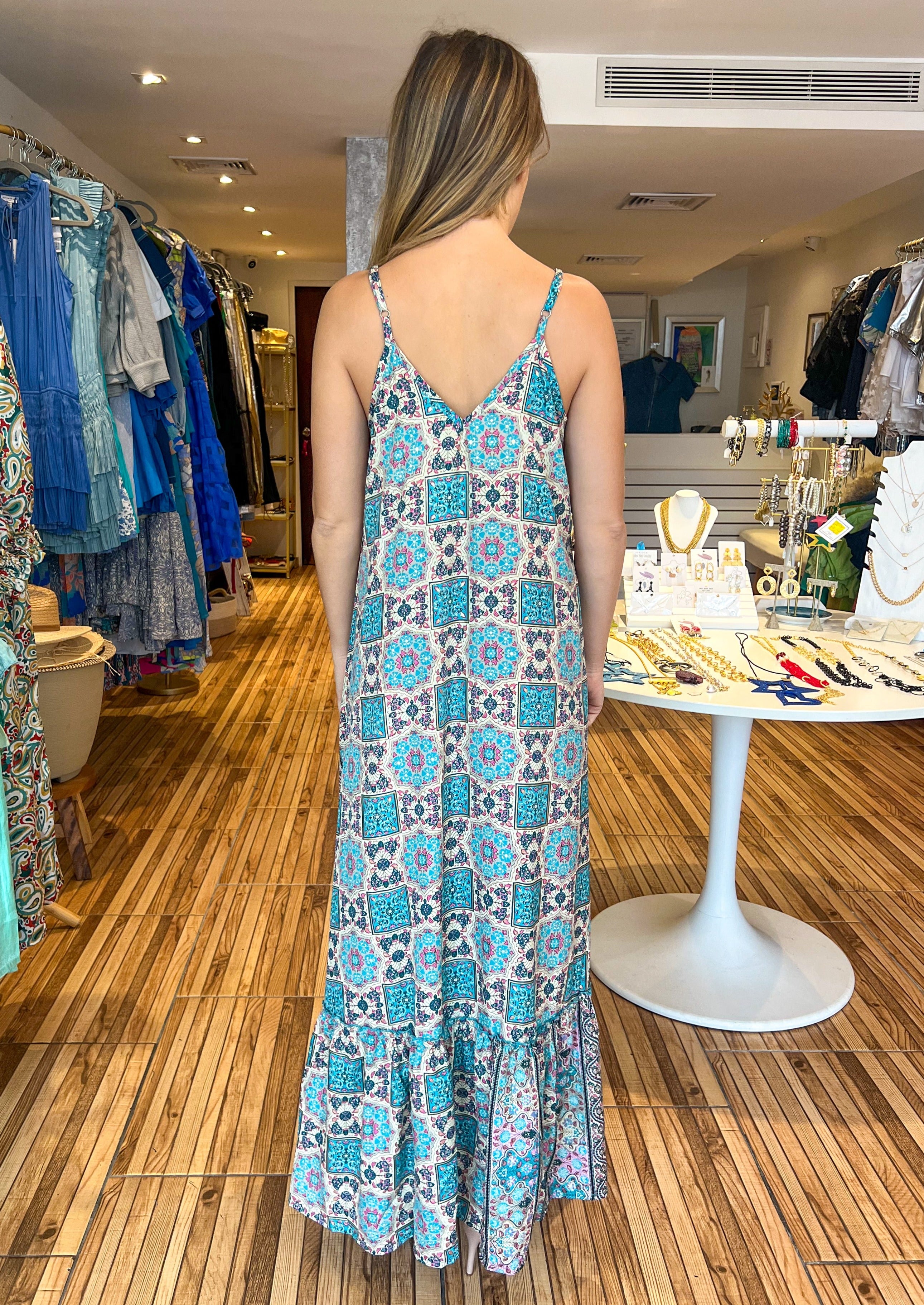 Turquoise and fuchsia printed maxi dress with adjustable straps, v-neckline, pockets, and a ruffle hem.