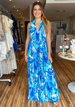 Load image into Gallery viewer, Blue printed woven jumpsuit featuring plunging V halter neckline, sleeveless, wide leg, self sash tie and bare back.
