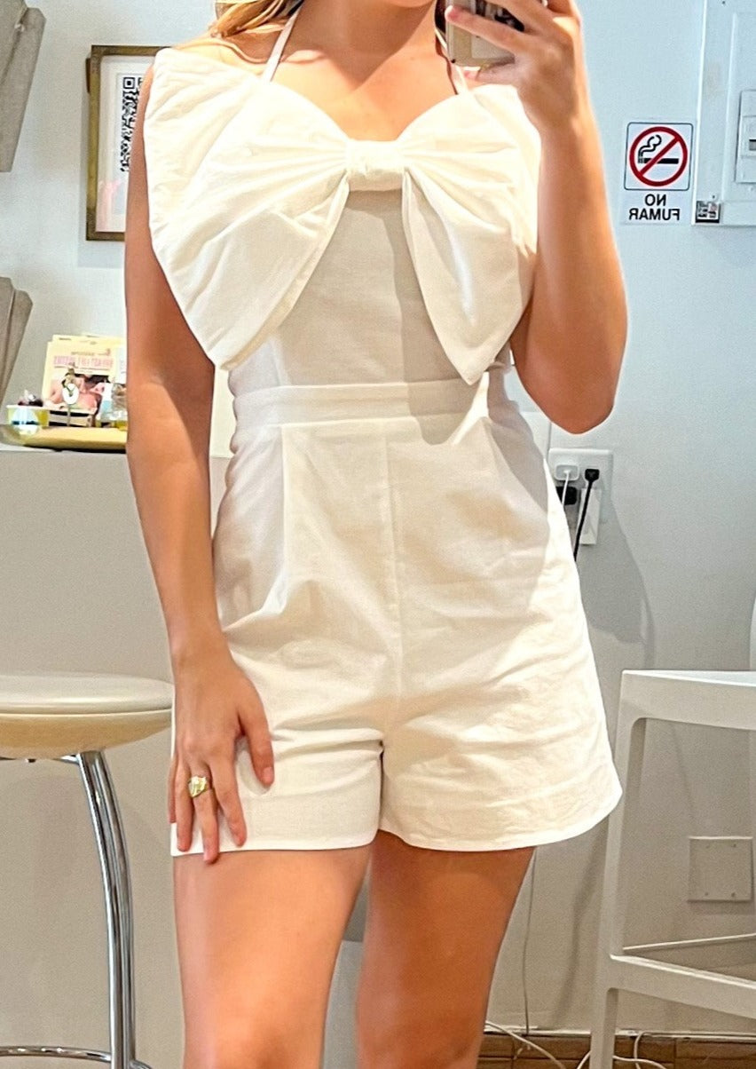 White romper with bow in the front. Halter, ties in the back. Elastic in the back.