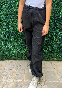 High waisted elastic waist band black cargo pants with pockets and side pockets. Bottom of the pants feature elastic so they can be worn loose or adjusted.