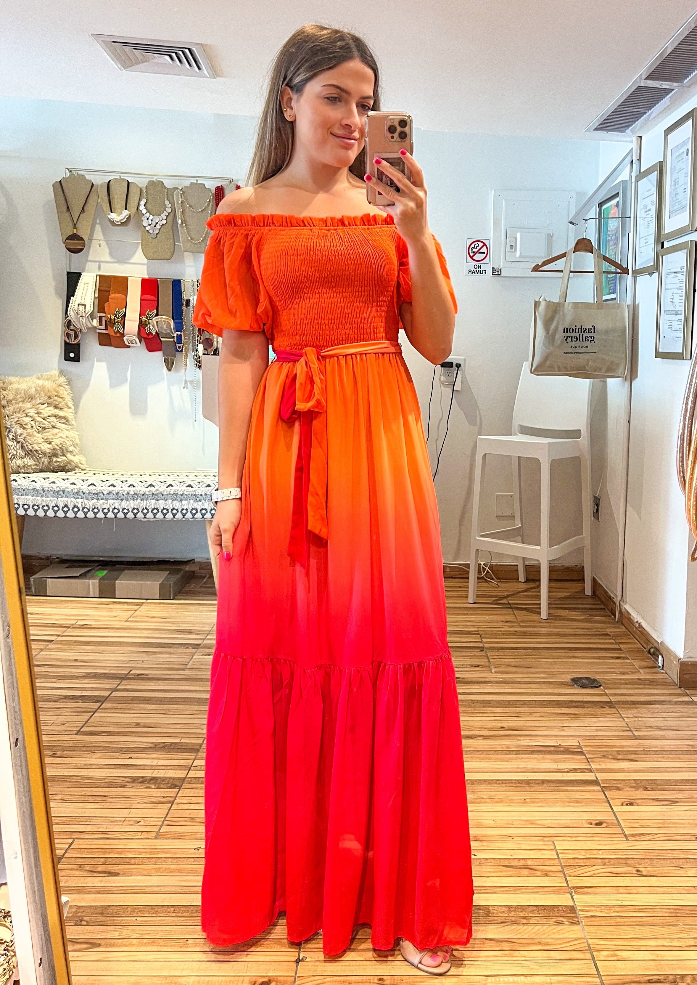 Orange fuchsia printed woven maxi dress featuring off shoulder neckline with ruffled edge, smocked bodice with self sash tie and ruffled hemline.