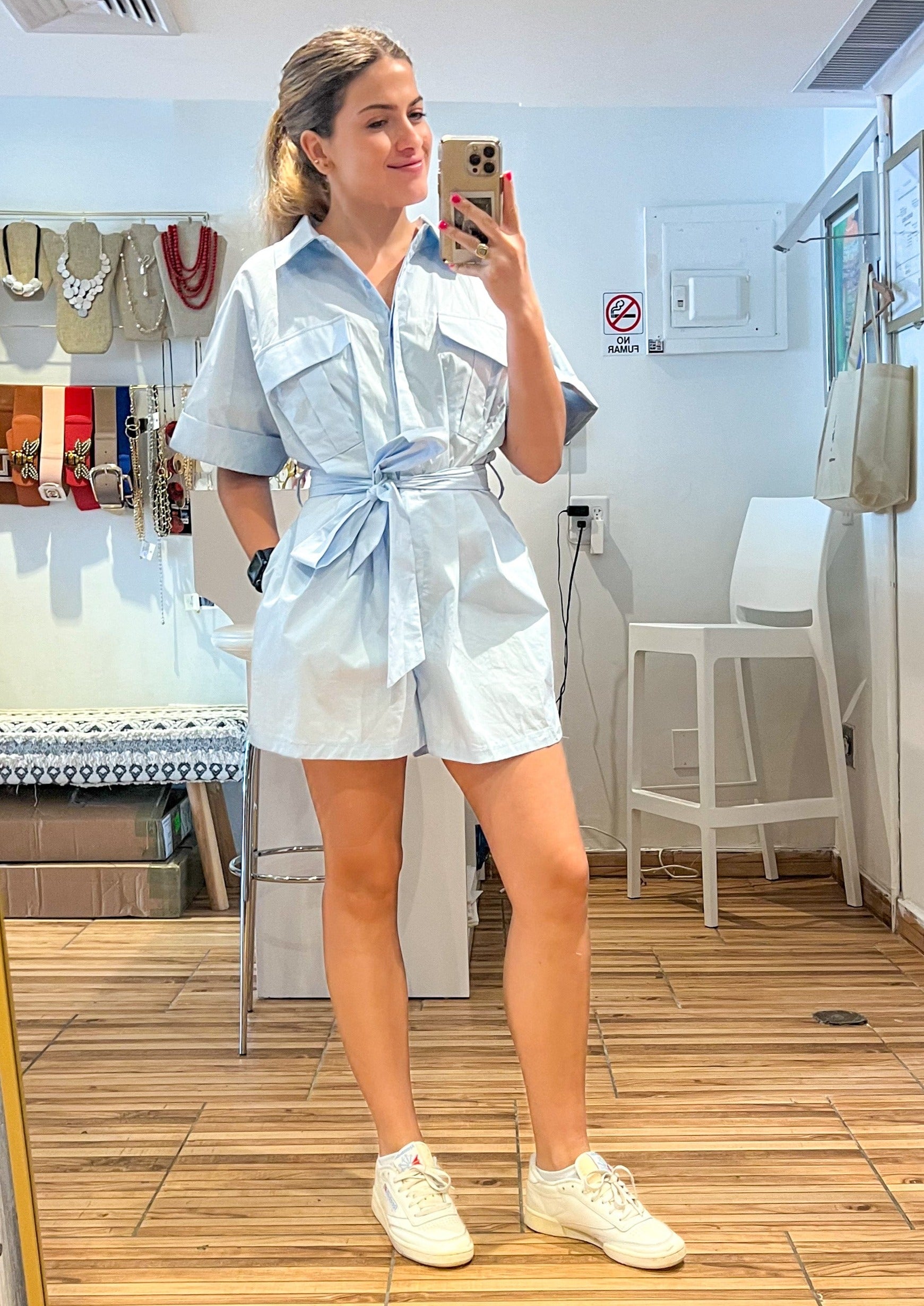 Baby blue button down romper with side pockets and self tie sash.