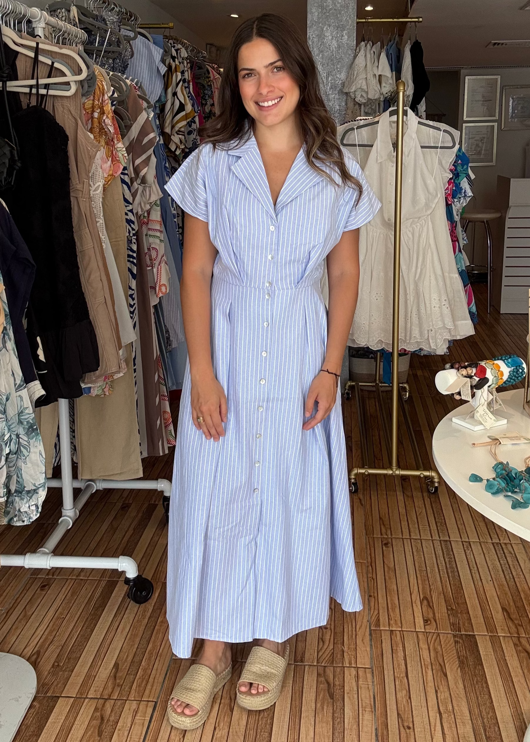 Woman in a blue striped dress standing in a clothing store.