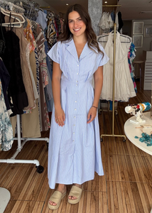 Woman in a blue striped dress standing in a clothing store.
