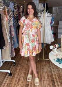 Woman in a floral dress standing in a clothing store.