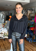 Load image into Gallery viewer, Ruffled blouse in washed satin fabric. This style features a classic V neck with tie closure, ruffle frill detail at yoke, and shoulders, and long sleeves with elasticated cuff.
