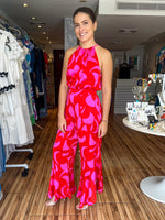Load image into Gallery viewer, Fuchsia and red color block halter jumpsuit with side slits with ruffle details. Jumpsuit adjusts at the waist. Very flowy and feminine.
