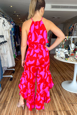 Load image into Gallery viewer, Fuchsia and red color block halter jumpsuit with side slits with ruffle details. Jumpsuit adjusts at the waist. Very flowy and feminine.
